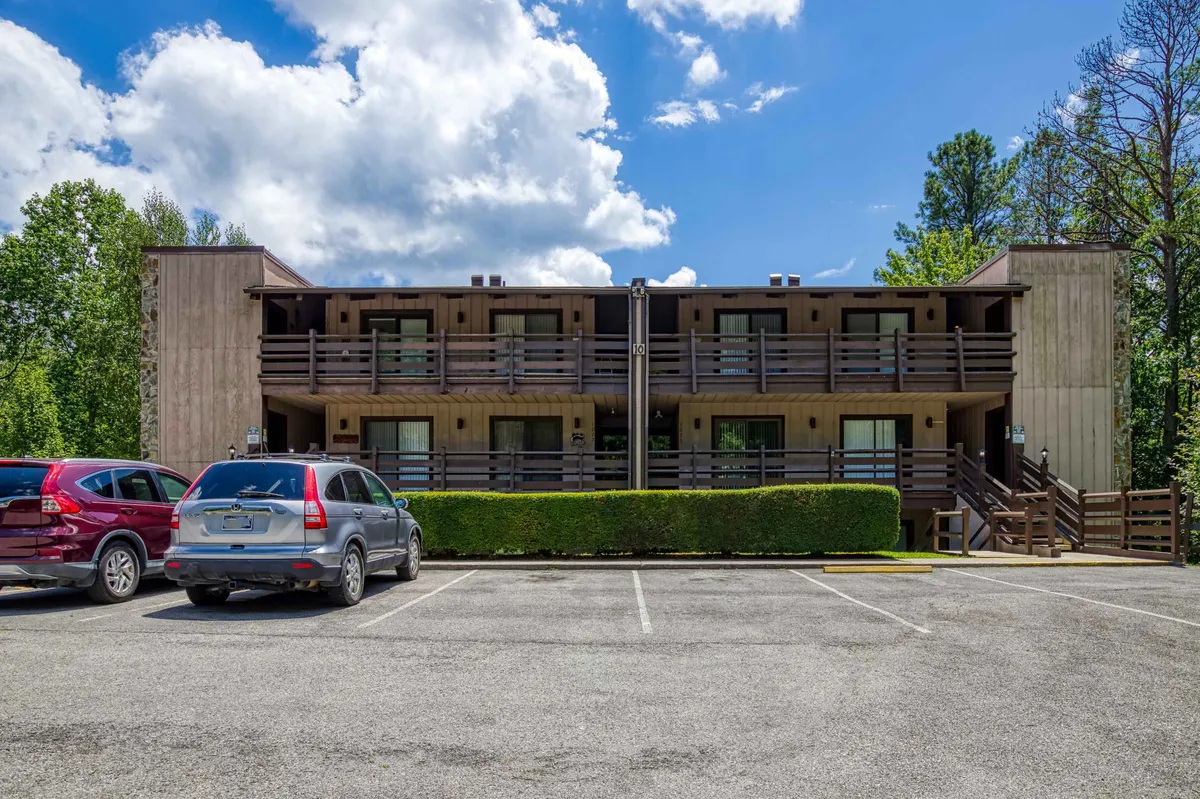A welcoming two-story building with balconies, a well-maintained parking lot, and green hedges. The exterior is inviting and suggests a comfortable, community-oriented space for families to relax and gather before or after adventures.