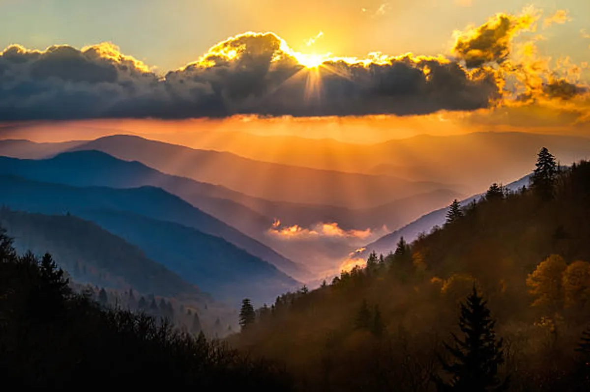 A majestic sunrise sweeps over a dramatic mountain range, with soft clouds and valleys stretching into the distance. The tranquil mood and expansive landscape evoke a peaceful start to the day, surrounded by nature's beauty and privacy.